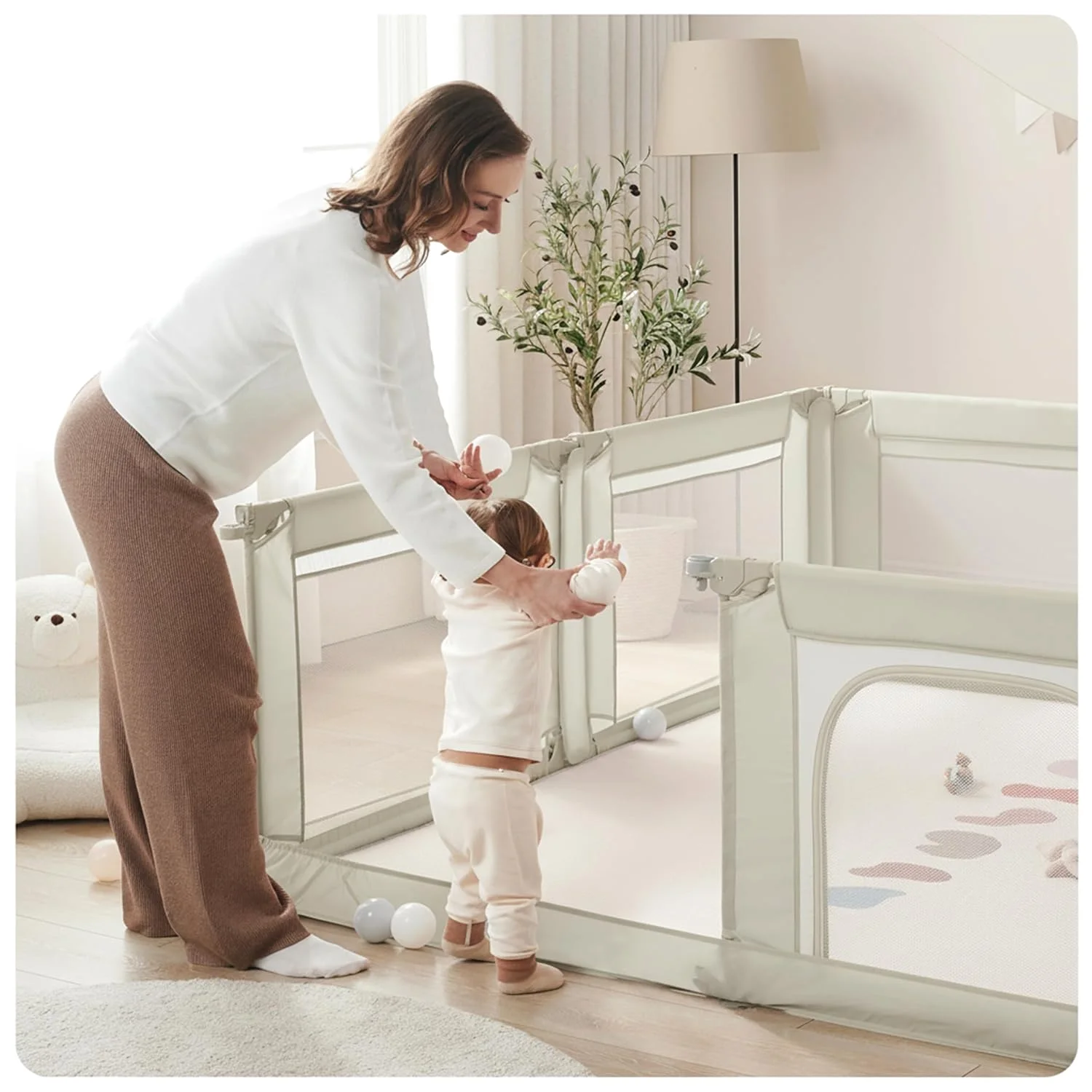 A parent setting a baby down in a Sweeby Modular Playpen