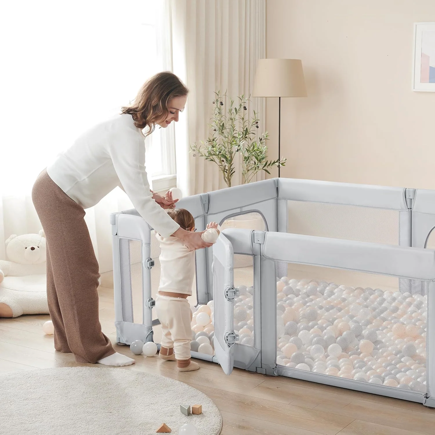A parent lifting a baby into a Sweeby Walk-In Gate Playpen